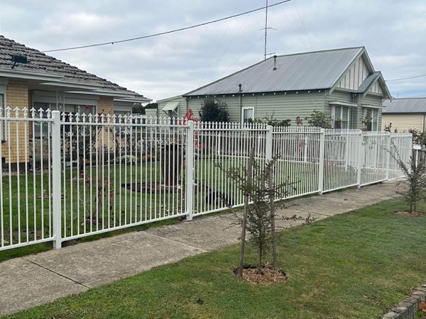 a white picket fence across the front of a weatherboard house