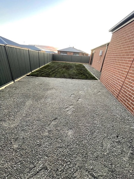 a gravel driveway running beside a Colorbond fence