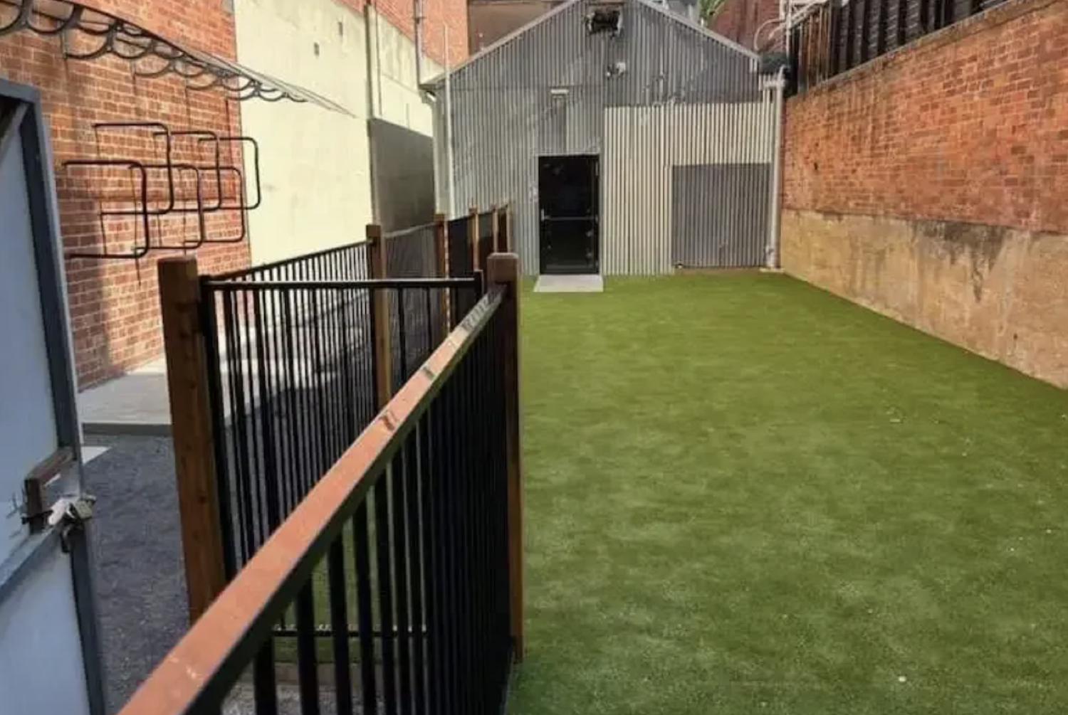 a black tubular steel gate between brick walls