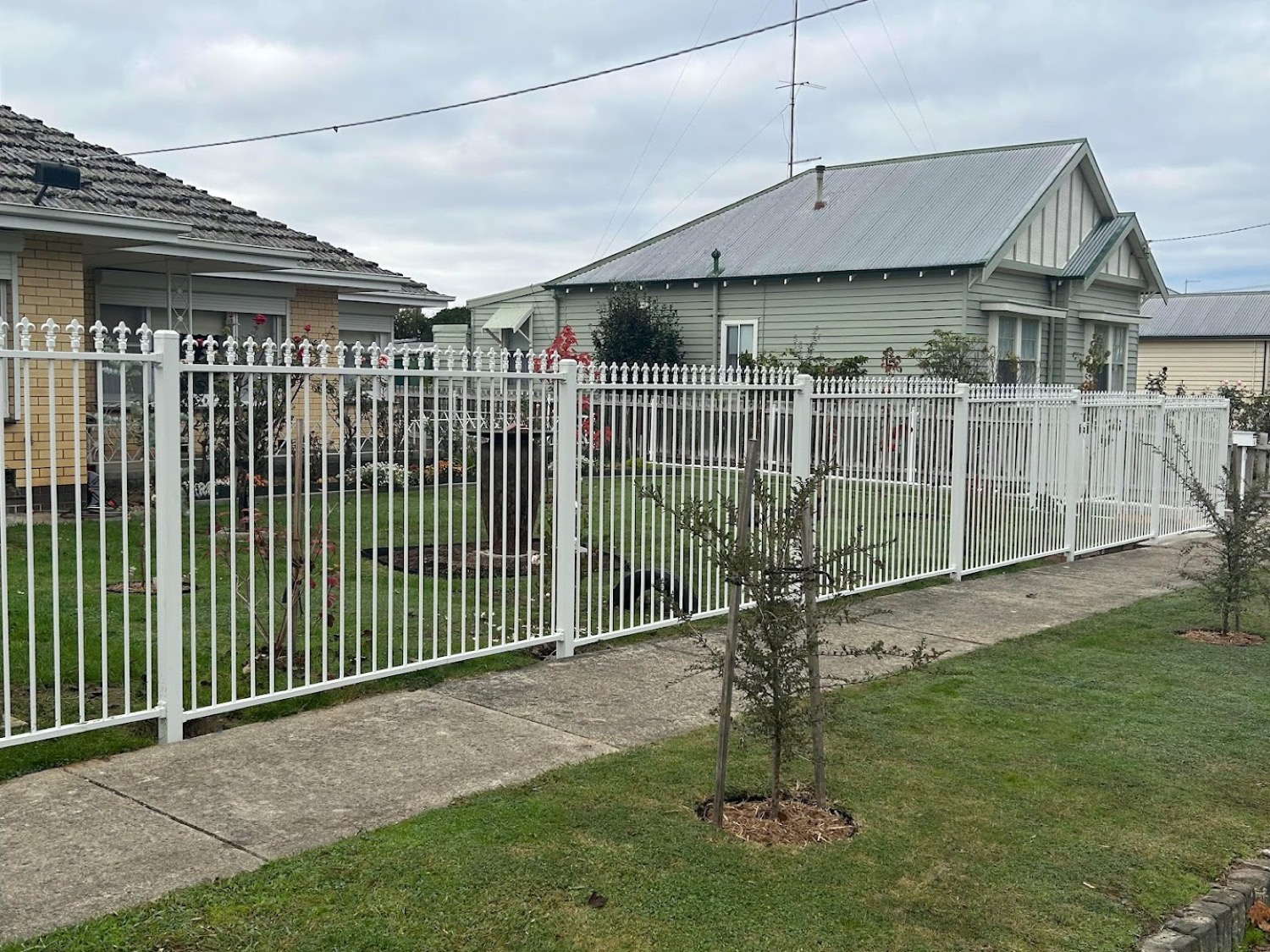 a white picket fence across the front of a weatherboard house