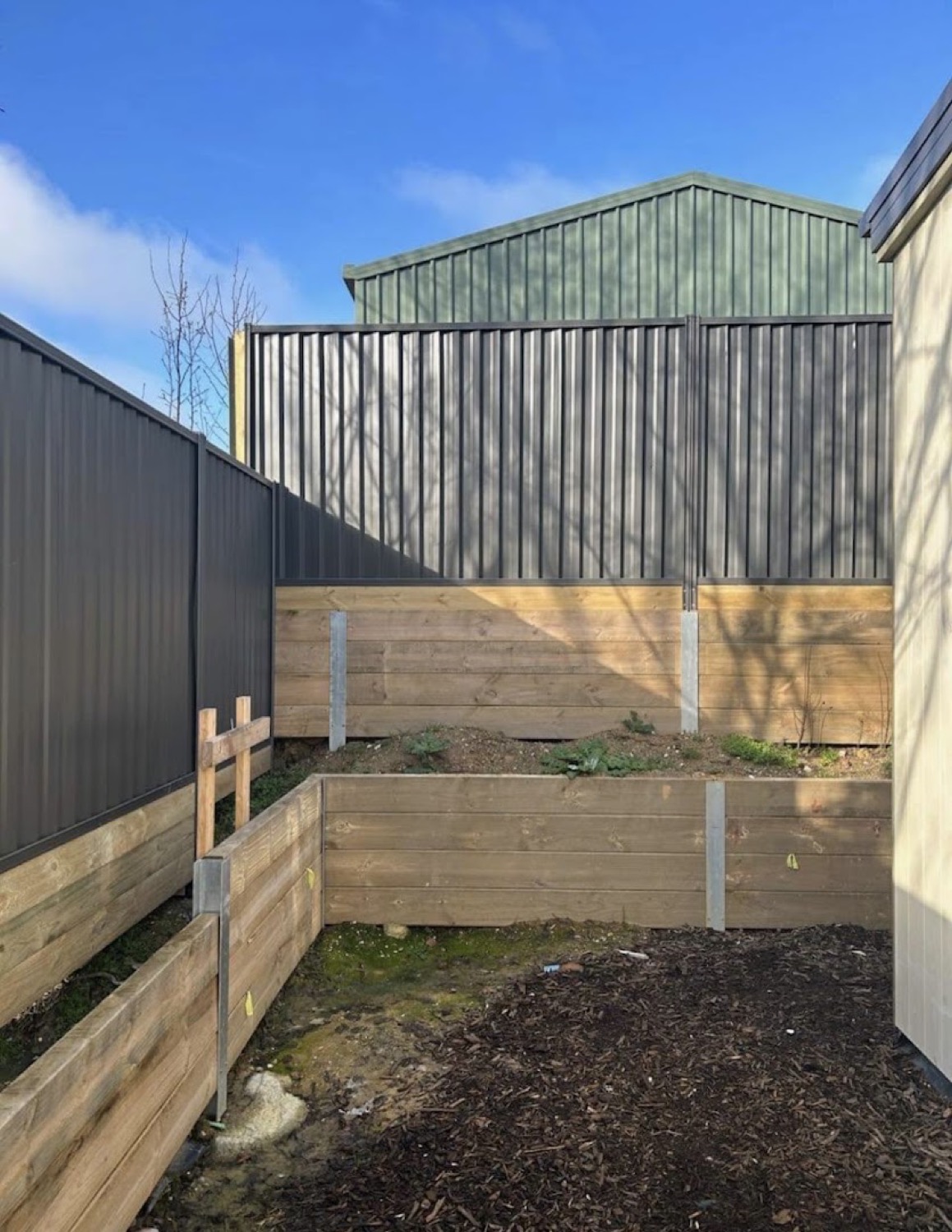 a Colorbond fence above a timber sleeper retaining wall