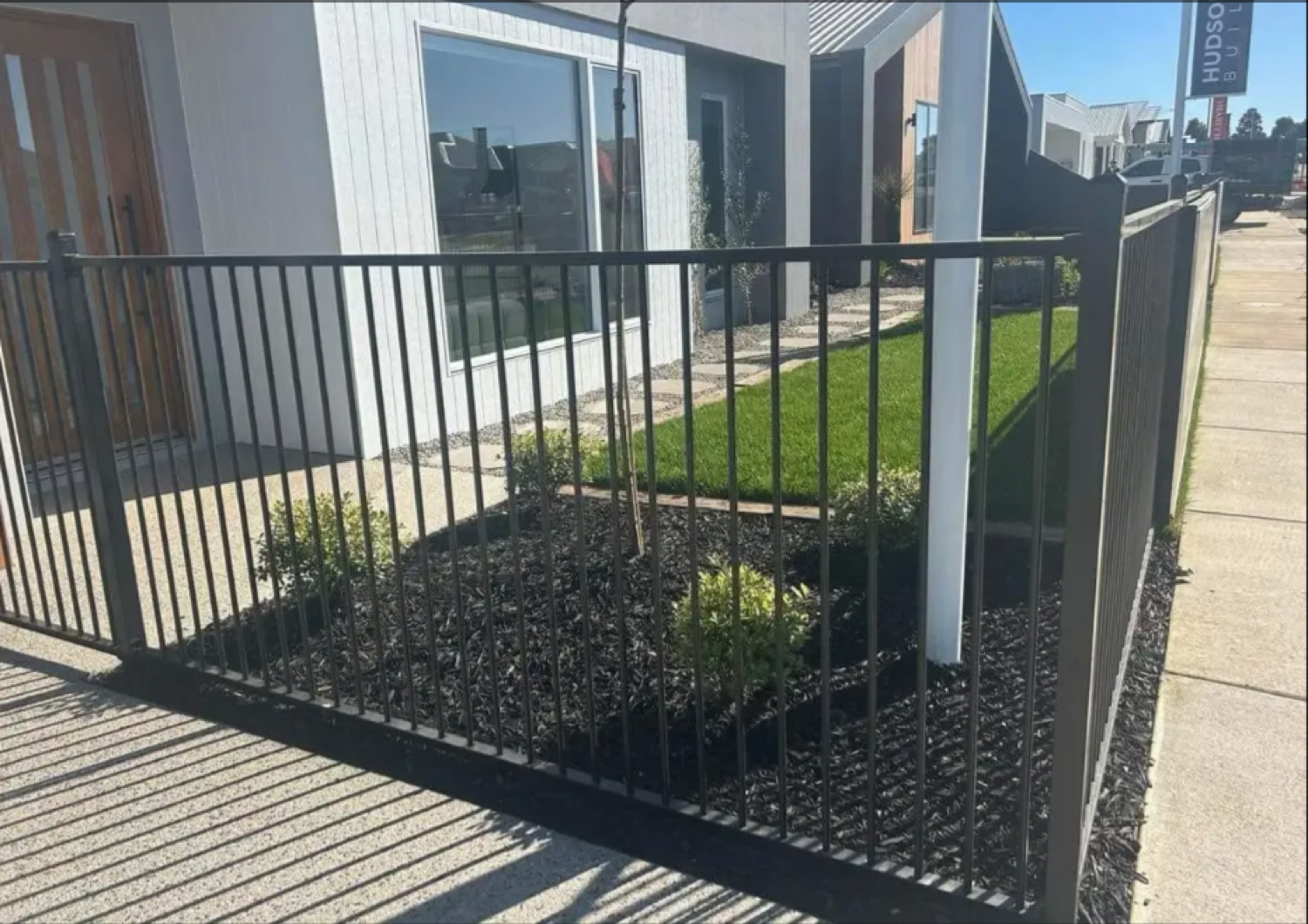 a black steel fence beside a garden bed and decking