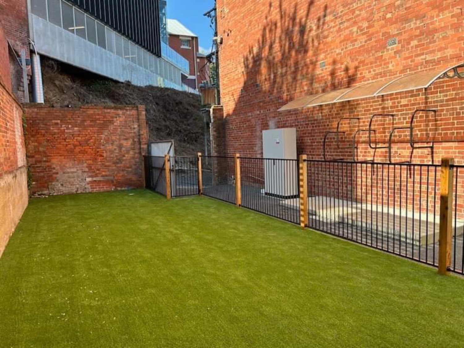 a black steel fence and gate beside a lawn area