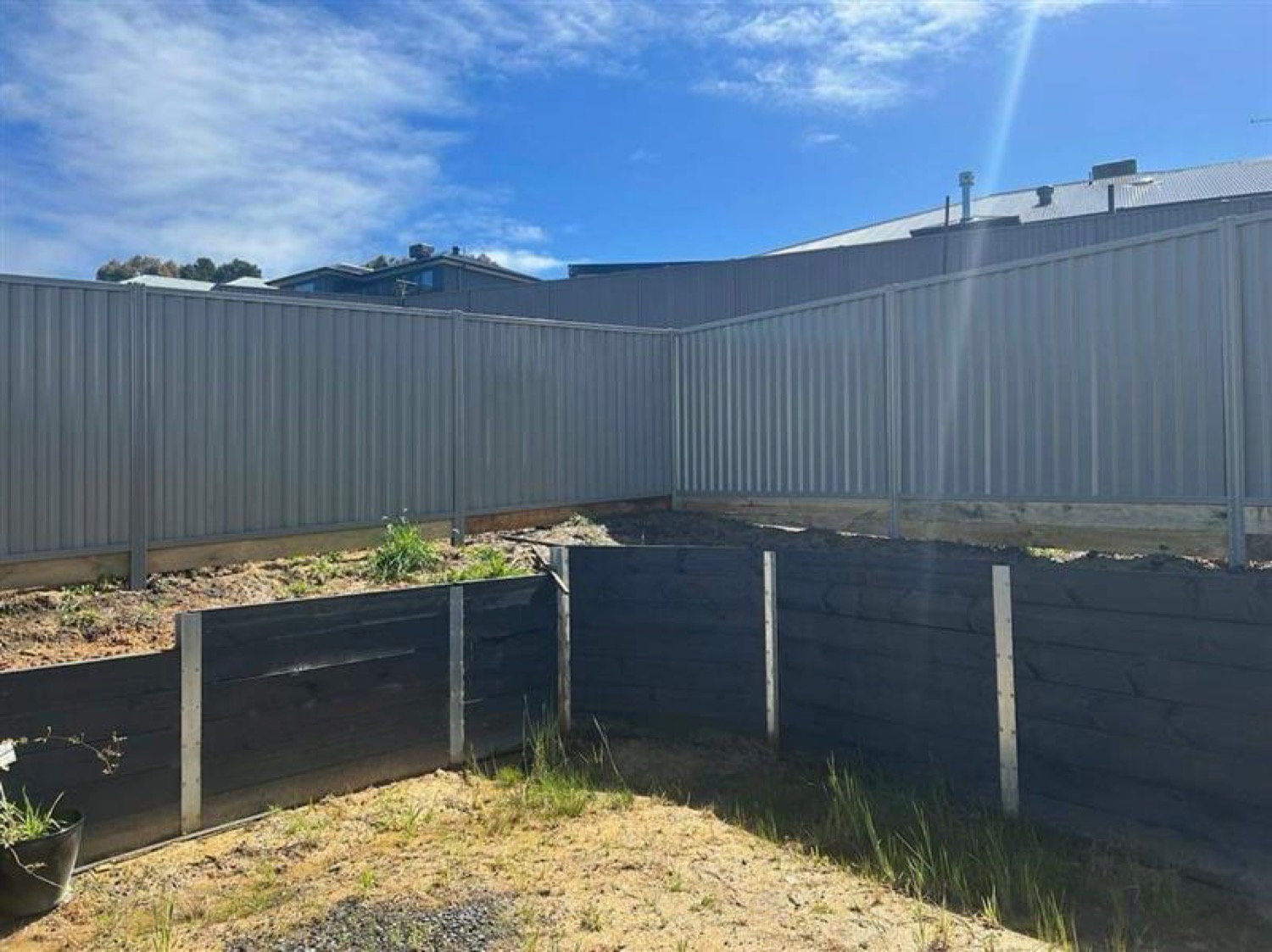 a Colorbond fence behind a sleeper-edged garden bed