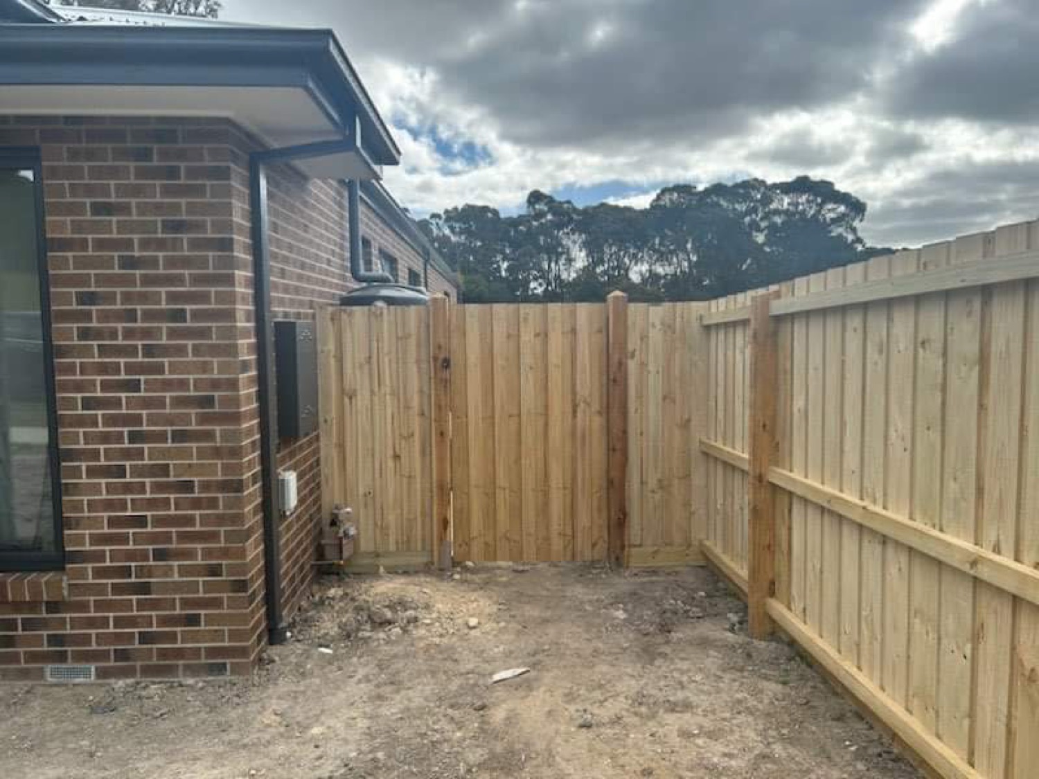 a timber paling fence meeting the corner of a brick house
