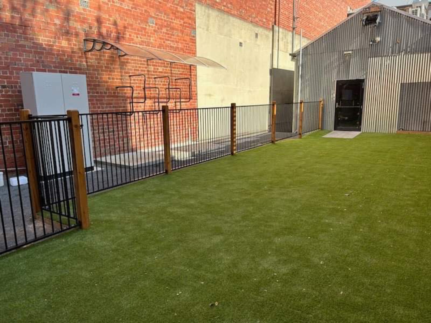 a black steel fence and gate around a turfed yard